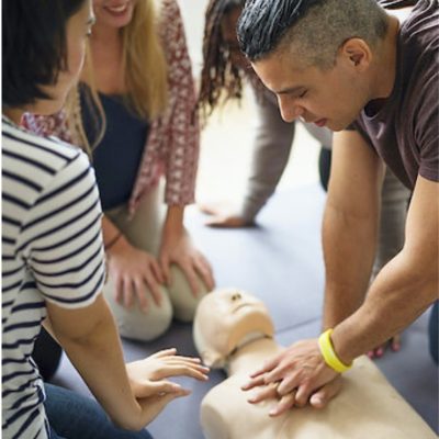 First Aid Course Awareness People practicing CPR on a mannequin during a training session for first aid awareness