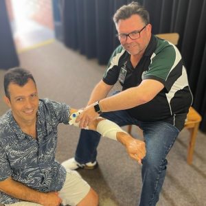 2 men practicing bandaging in a HLTAID011 Provide First aid class at their workplace in Brisbane