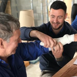 2 men practicing bandaging at a HLTAID011 Provide First Aid inc CPR class in Ipswich