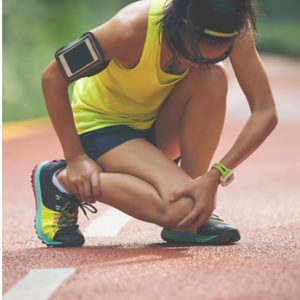 Runner in athletic gear kneels on a track, holding her knee in apparent pain. Learn Sports Trainer refresher course
