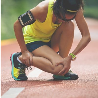 Runner in athletic gear kneels on a track, holding her knee in apparent pain. Learn Sports Trainer refresher course