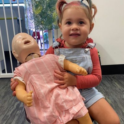 toddler holding annie the cpr manikin promoting online courses for childcare educators