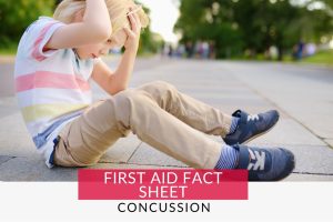 Boy clutching his head on the floor with potential concussion