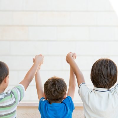 children with their arms up and backs to the camera learning junior safety and and wellbeing