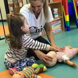 parent doing a first aid class with her child and teaching her cpr on a baby annie manikin. parenting first aid