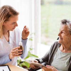 Woman assisting elderly with medication after Medication Administration Refresher Training