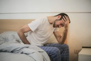 man on bed fatigued, impact of high stress and poor work life balance