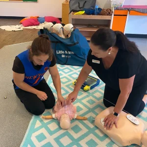 performing CPR on an infant manikin at a childcare staff training session. First Aid and CPR training for childcare educators