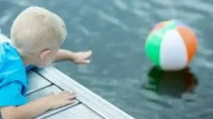 Child reaching for a ball in a swimming pool