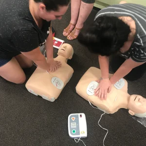 ladies demonstrating use of defib, learn cpr and how to use a defibrillator correctly. CPR courses in Ipswich